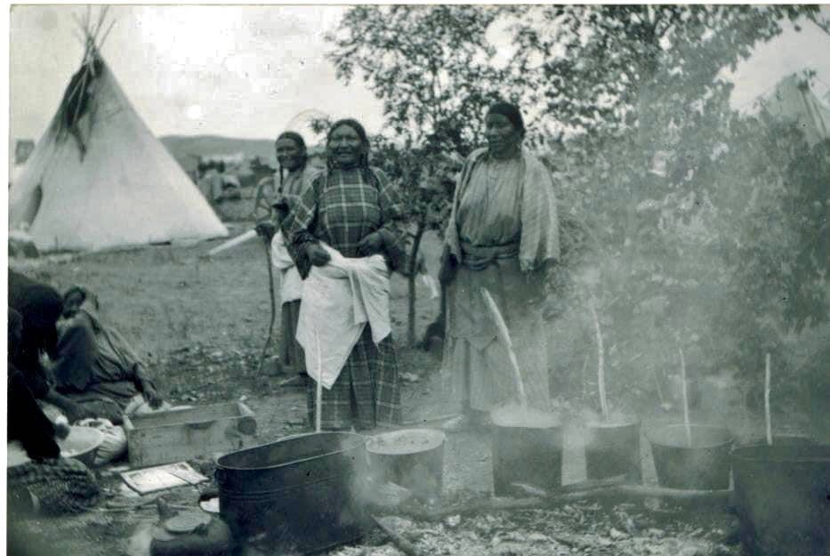 Sioux ladies preparing meat for a feast at the Crow Agency campgrounds. / Photographer unknown, 1886.