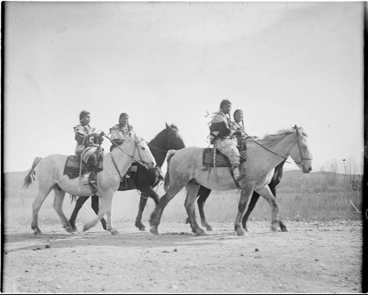 Sioux Girls parade past Gas Cap Hill during a celebration in Crow Agency. / Historic photo from the Fred Miller Collection at the Smithsonian National Museum of the American Indian
