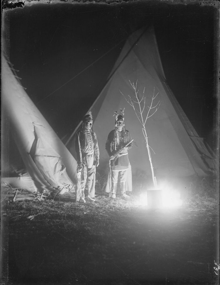Two Apsaaloke men stand in camp in 1886. This photo is an example of one of the first uses flash photography in the United Sates. / Fred Miller Collection, Smithsonian Institute